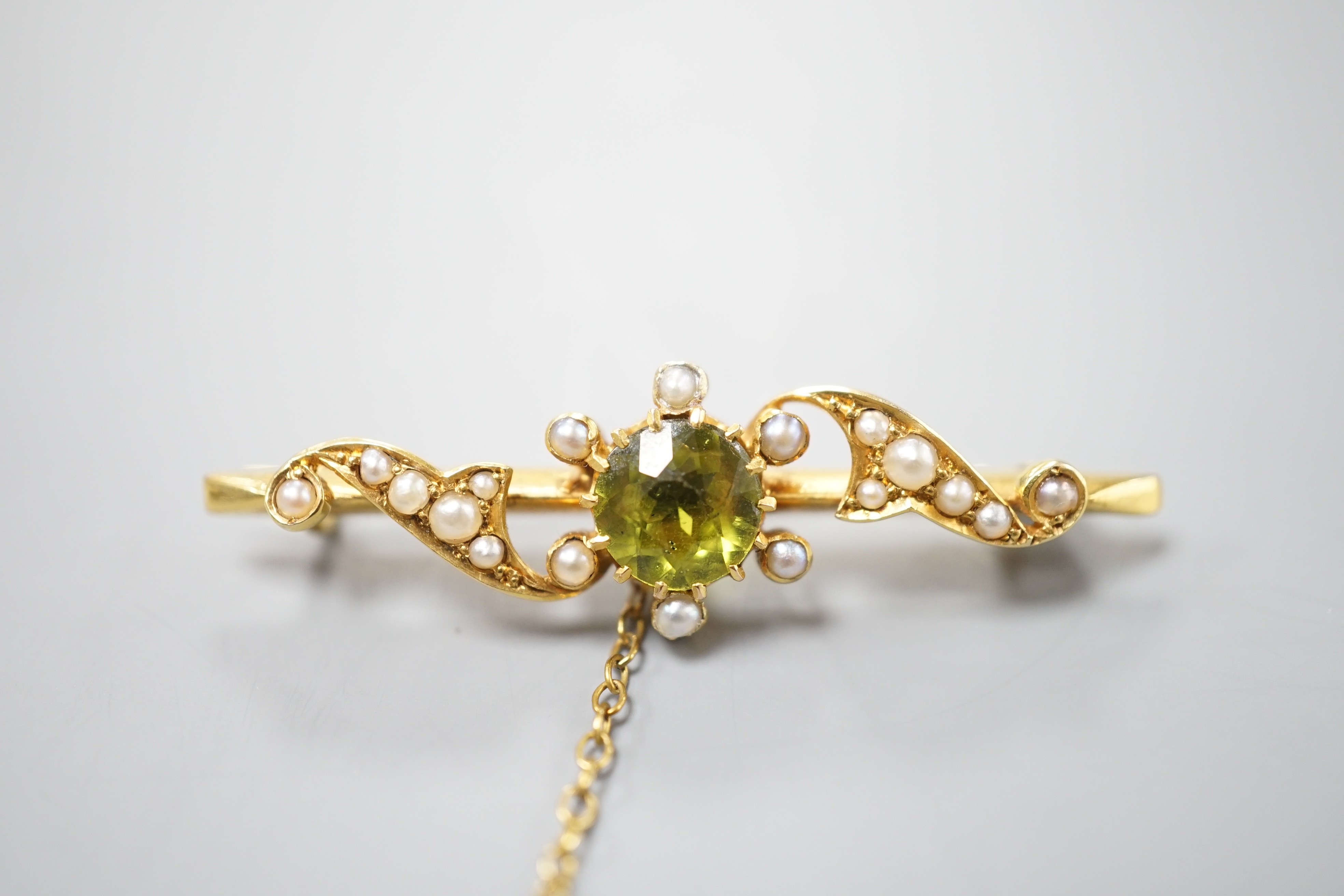 An Edwardian 15ct, peridot and seed pearl set bar brooch, 43mm, gross weight 4.2 grams.
